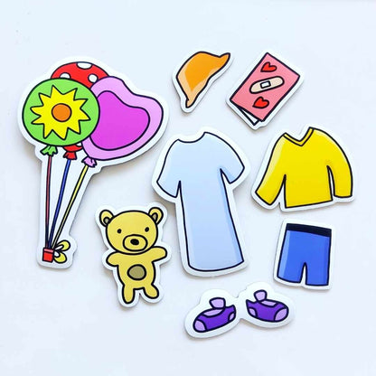 The non-medical set pieces are displayed against a white background: a cozy yellow sweater, blue shorts, purple slippers, orange hat, a get well card showing a band-aid and hearts, a bunch of 3 colourful balloons, and a friendly stuffed teddy bear.